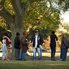 Group of individuals stand outdoors. 