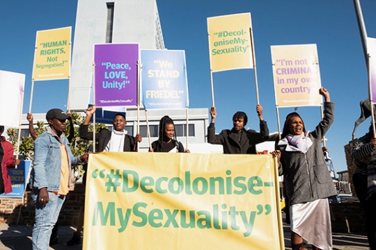 Protesters hold sign reading "Decolonise My Sexuality".