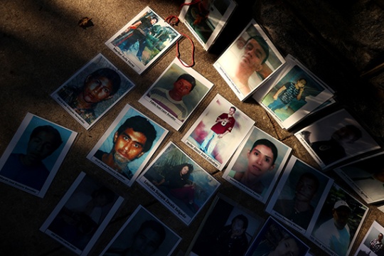 Multiple posters of missing individuals lie on floor. 
